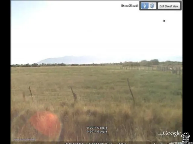 Open land parcel featuring native vegetation, a perimeter wire fence, and distant mountain topography