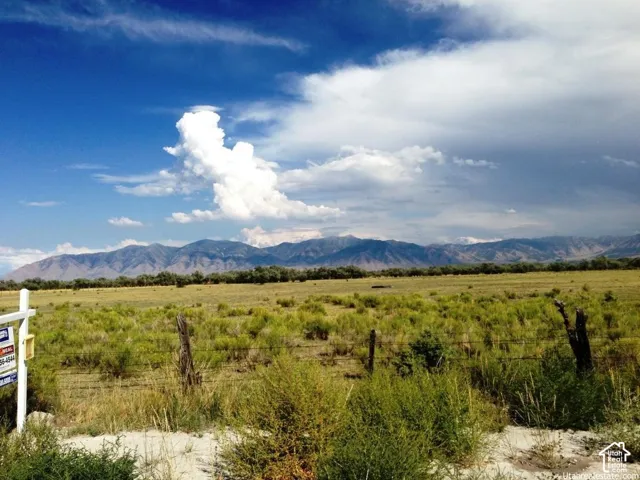 Expansive lot featuring native vegetation, a wire-strand fence, and prominent mountain backdrops