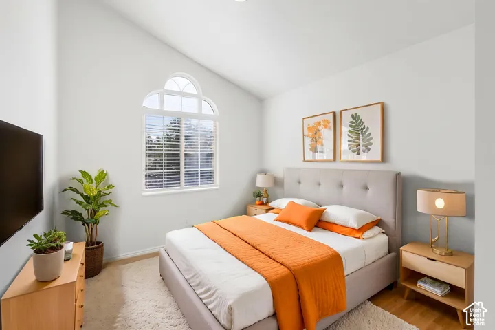 Vaulted ceilings, wood-finish flooring, and a decorative arched window