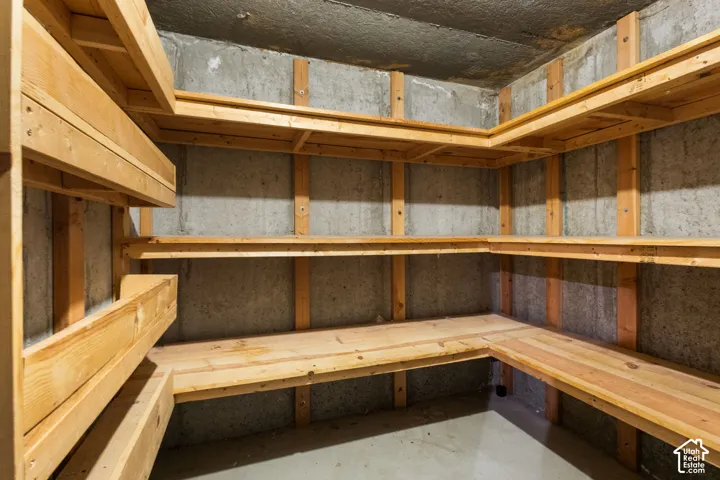 Storage area featuring multi-tier wood shelving units and unfinished concrete walls