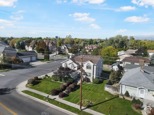 Corner lot residence featuring a multi-story exterior, shingled roofing, manicured lawn, and professional landscaping