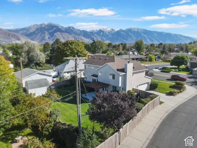 Two-story residence featuring a wood pergola, manicured lawn, fenced backyard, and a mountain backdrop
