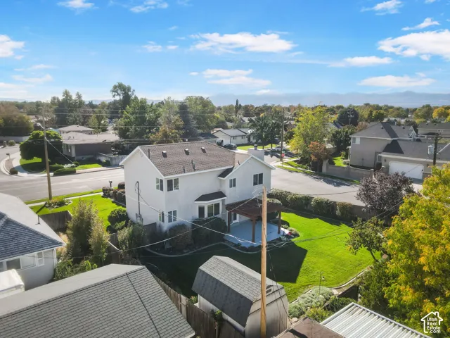 Corner lot property featuring a multi-level exterior, fenced rear yard with manicured lawn, attached wood-frame pergola, and exterior storage shed