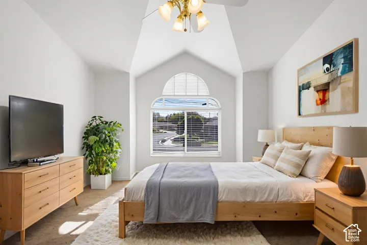 Vaulted ceiling featuring an arched window with an integrated blind, wall-to-wall carpeting, and an attached multi-arm ceiling fan with light fixtures