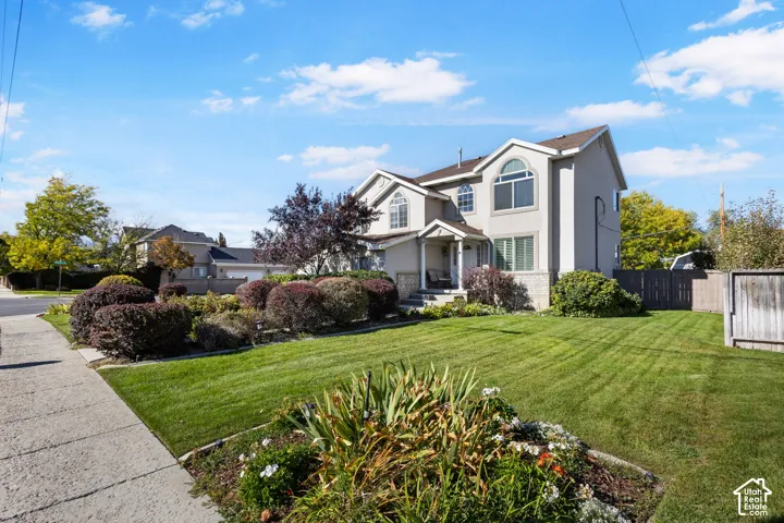 Multi-level exterior featuring light-toned siding, stone veneer accents, arched windows, and a landscaped front yard with manicured lawn and mature shrubs
