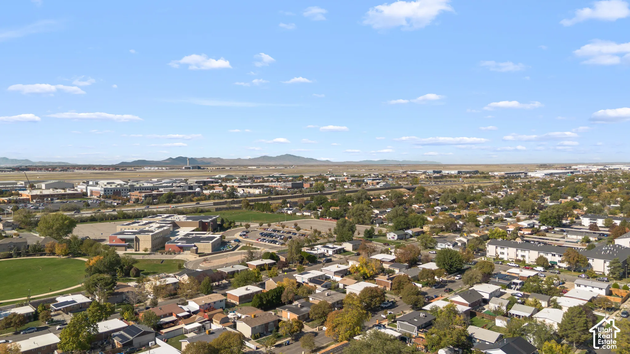 Aerial perspective of the surrounding residential landscape featuring prominent mountain scenery and expansive sky