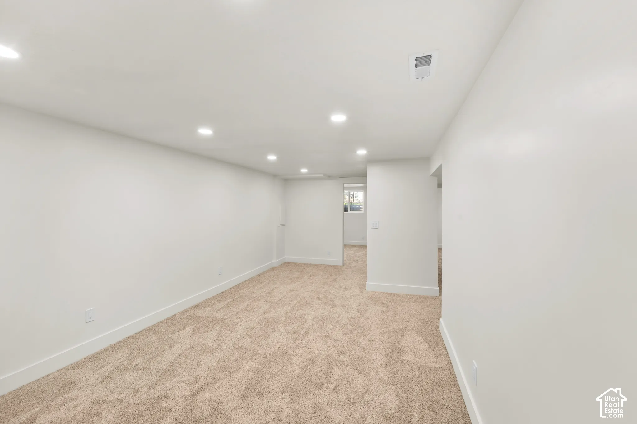 Neutral interior space featuring high-pile wall-to-wall carpeting, crisp white walls, and recessed ceiling lighting