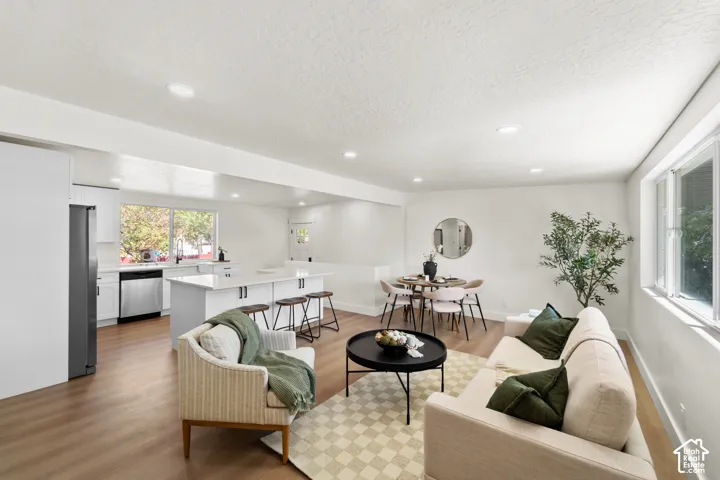 Open-concept interior featuring wood-finish flooring, recessed lighting, and a kitchen island with white cabinetry and a solid-surface countertop