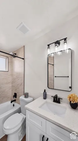 Bathroom featuring a white vanity with a speckled stone countertop, an integrated rectangular sink, matte black fixtures, and a glass-enclosed shower with neutral-toned tiled walls