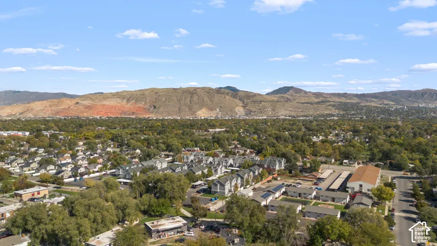 Aerial perspective of suburban landscape featuring expansive mountain ranges, mature trees, and established street grids
