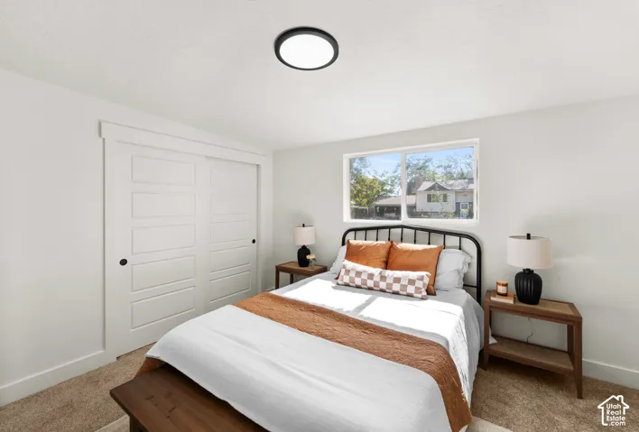 Neutral-toned room featuring wall-to-wall carpeting, a horizontal sliding window, and a white sliding closet door with a shaker-style panel design, completed by a matte black circular flush-mount ceiling light fixture