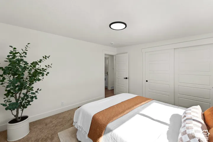 Neutral interior featuring crisp white walls, carpeted flooring, a circular flush-mount ceiling light, and white five-panel doors with matte black hardware