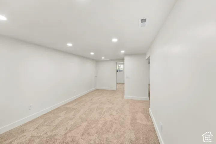 Neutral interior space featuring high-pile wall-to-wall carpeting, crisp white walls, and recessed ceiling lighting