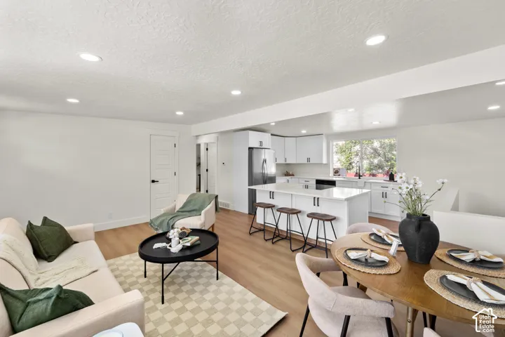 Open-concept kitchen featuring white cabinetry, center island with stone-finish countertops, recessed lighting, and wood-finish flooring throughout