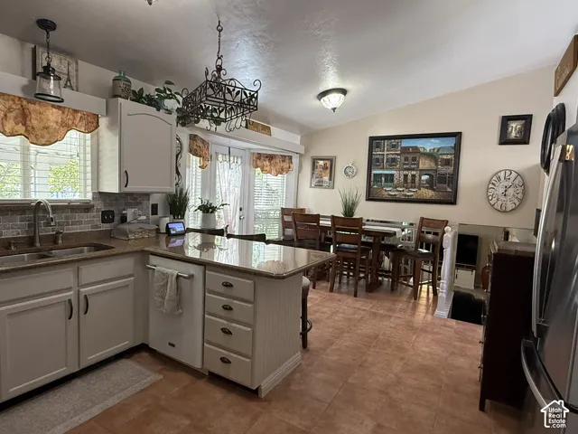 Kitchen featuring cabinetry with crown molding, solid-surface countertops, tile flooring, and decorative metal light fixtures