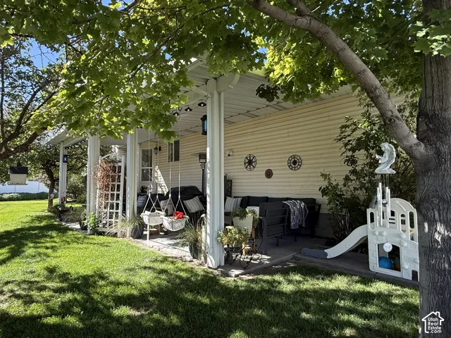Covered patio featuring a concrete slab, support columns, and siding exterior, complemented by a manicured lawn and mature trees