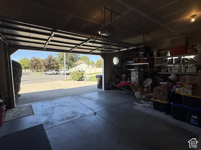 Attached garage featuring a concrete floor, an overhead automatic garage door opener, and an octagonal accent window