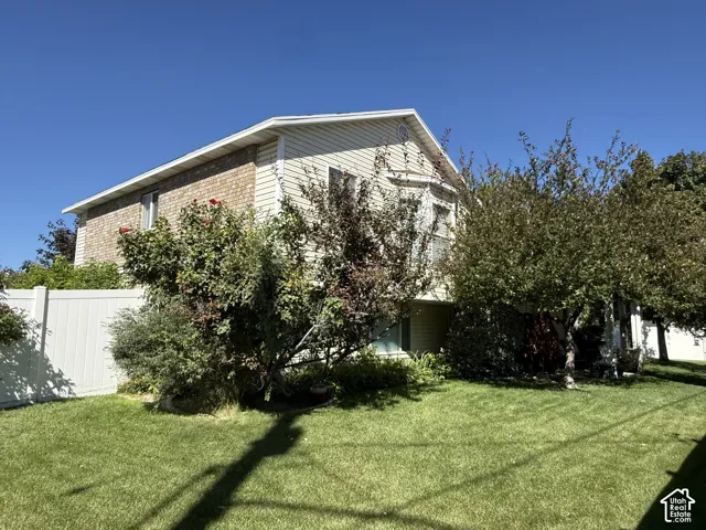 Two-story residence featuring light-colored horizontal siding, brick exterior accents, and a vinyl privacy fence encompassing the lawn area