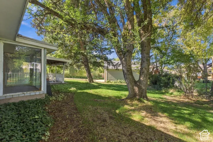 Screened-in porch featuring white structural railing, expansive rear grounds with mature trees, and detached garage