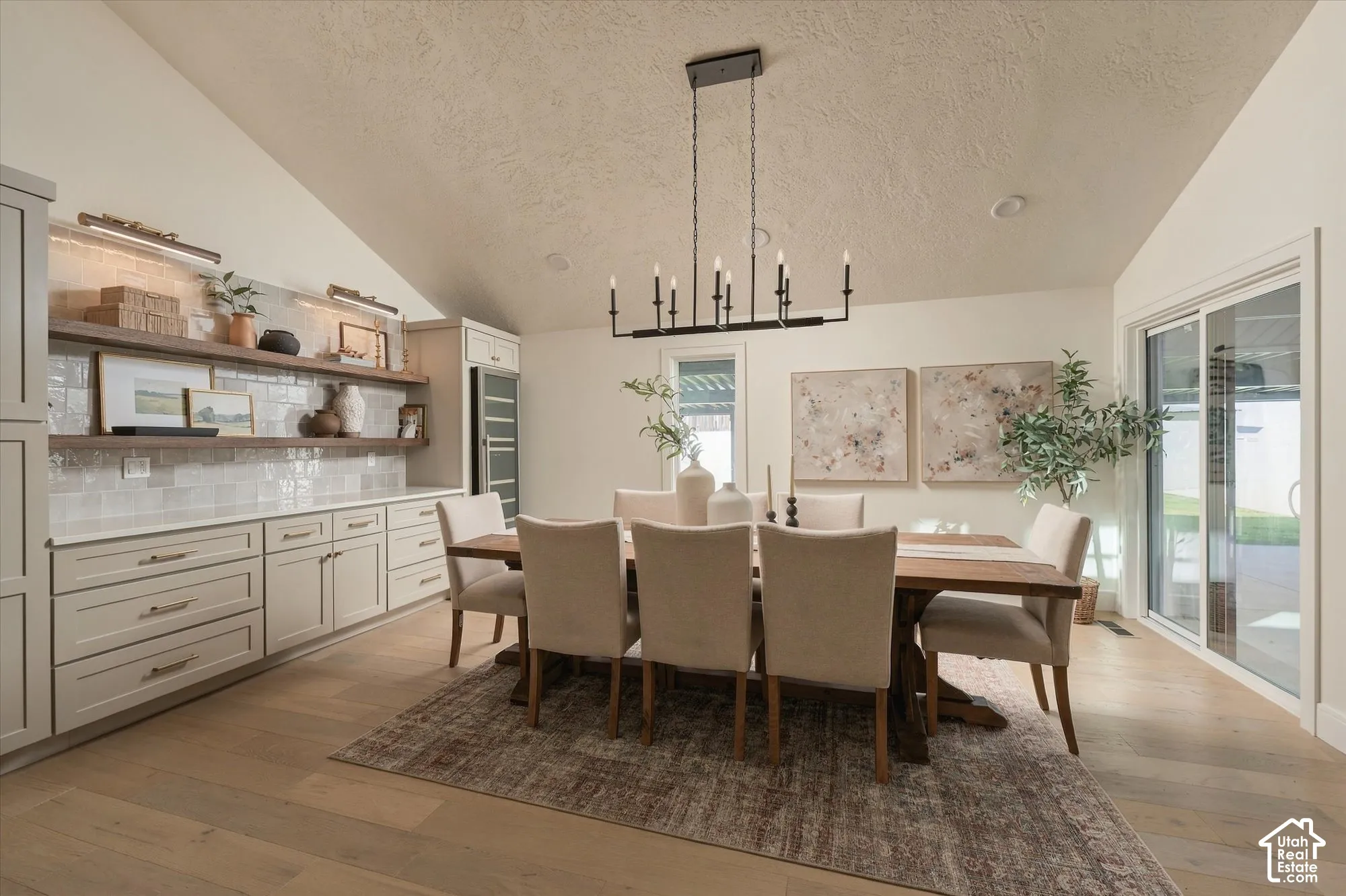 Vaulted ceilings, wood-finish flooring, custom built-in cabinetry, subway tile backsplash, and sliding glass door
