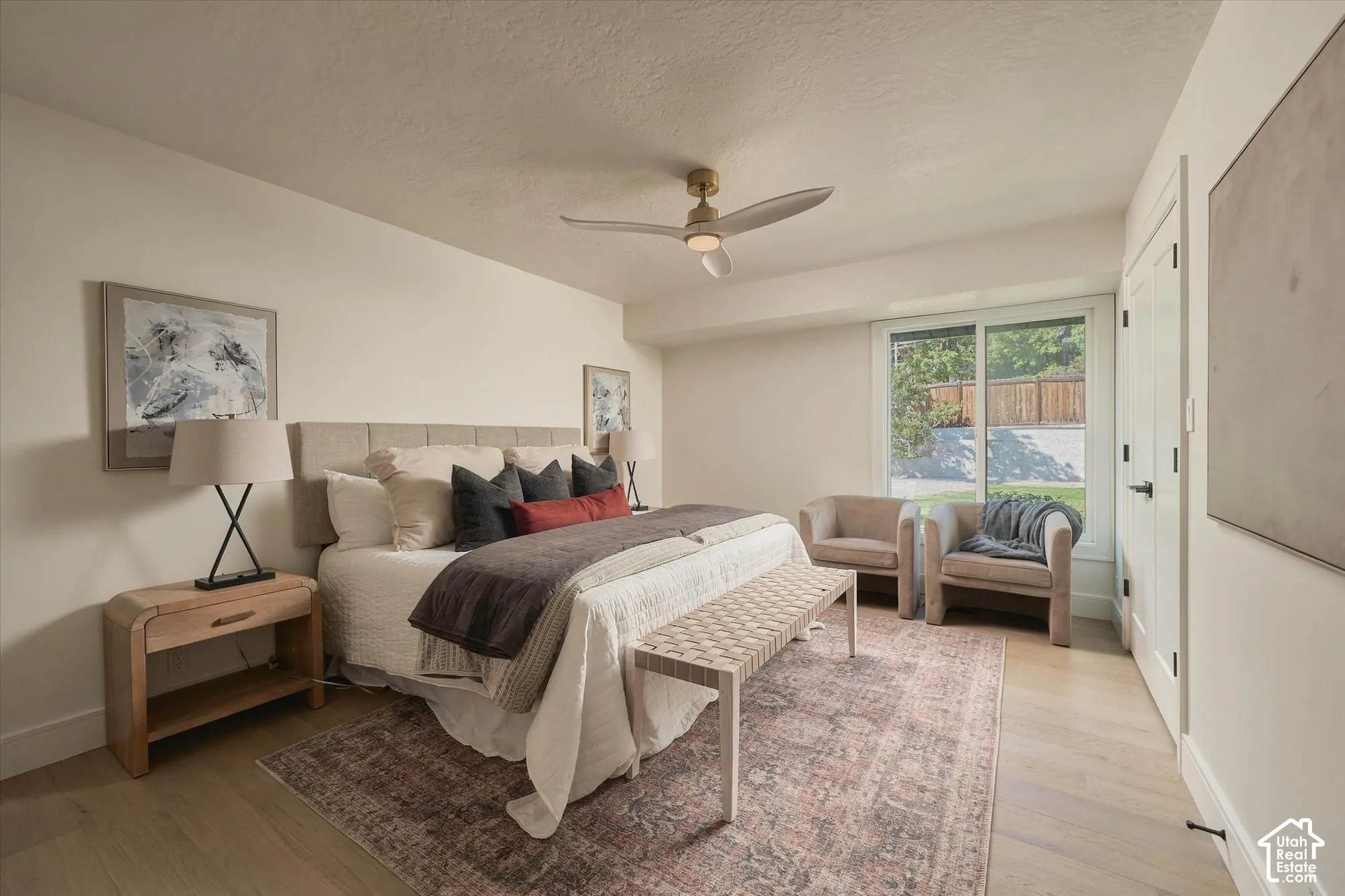 Neutral-toned room featuring wood-finish flooring, a contemporary three-blade ceiling fan with integrated lighting, and a sliding glass door