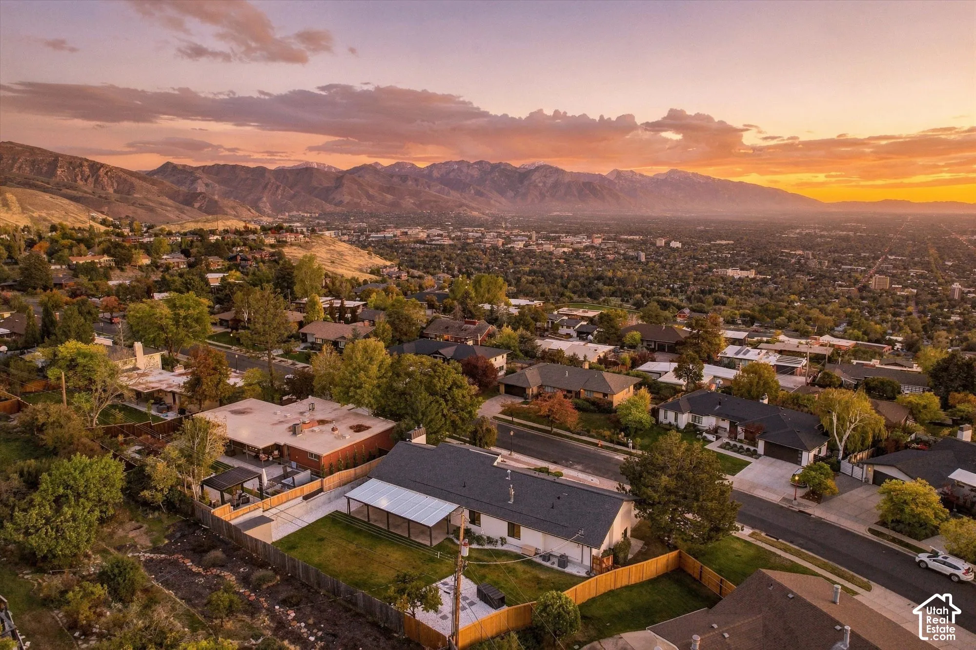 Aerial perspective featuring a sprawling landscape with prominent mountain silhouettes and a sunset horizon