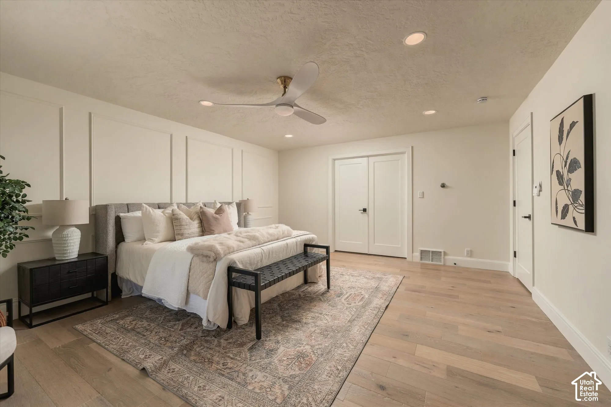 Room featuring wood-finish flooring, wainscoting wall detailing, a three-blade ceiling fan, and recessed lighting