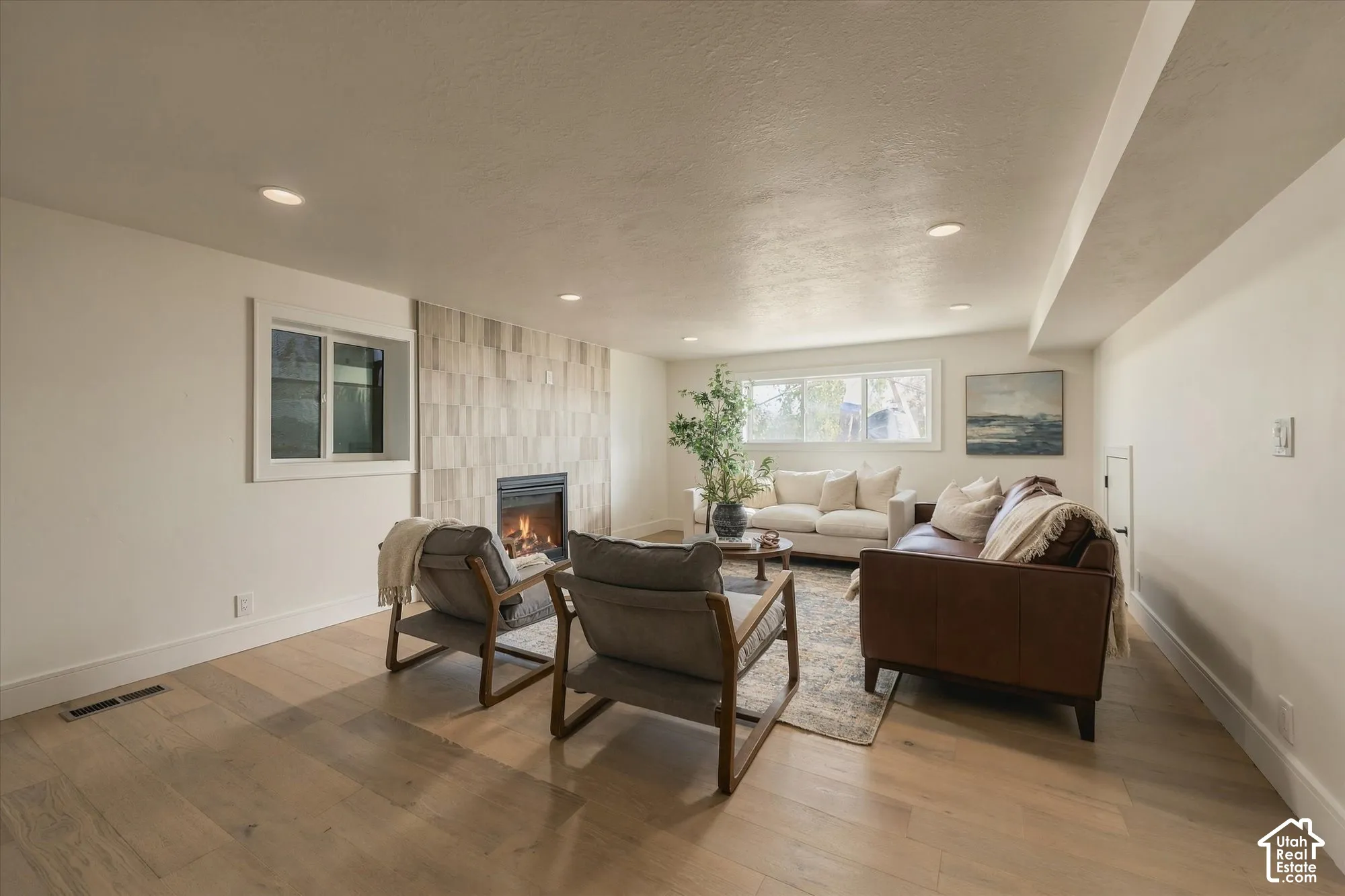 Living area featuring wood-finish flooring, recessed lighting, and a floor-to-ceiling textured tile fireplace surround