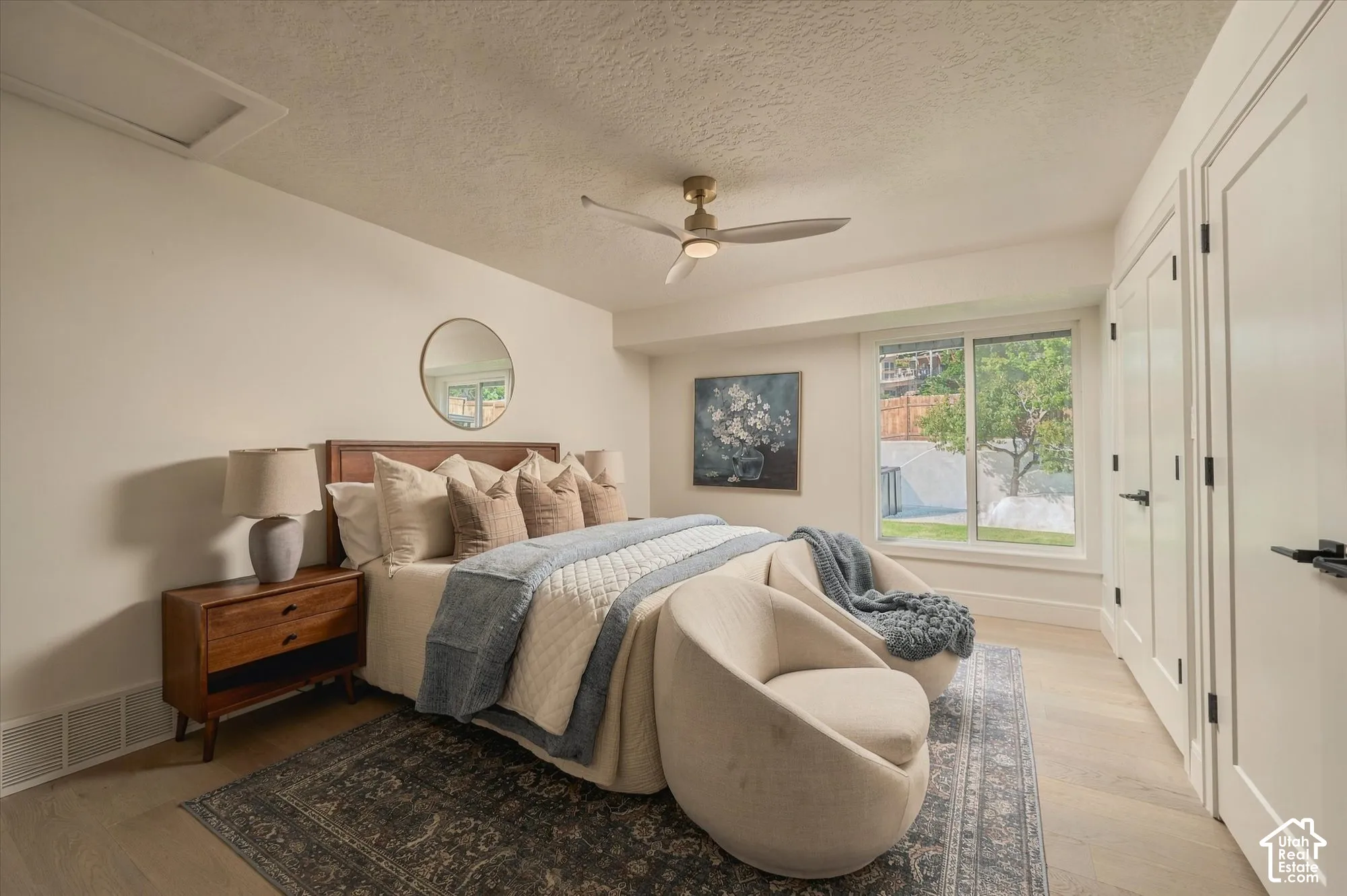Room featuring wood-finish flooring, a sleek ceiling fan with integrated lighting, a sliding glass window, and a multi-panel door with matte black hardware