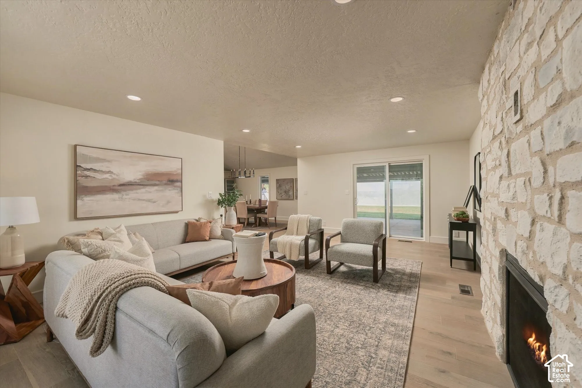 Floor-to-ceiling stone fireplace, wood-finish flooring, recessed lighting, and sliding glass doors