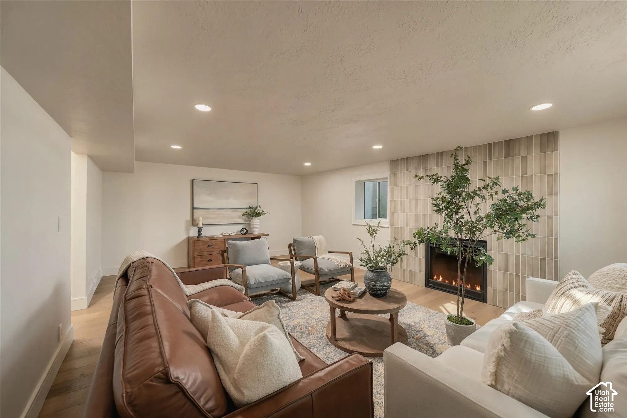 Fireplace featuring a full-height, vertically-oriented neutral stone tile surround, recessed lighting, and wood-finish flooring