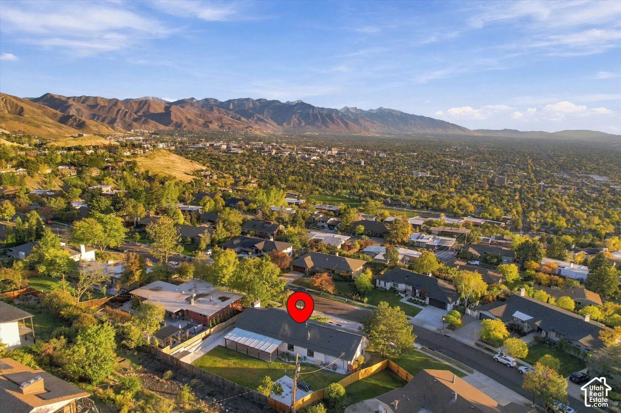 Aerial perspective of a property featuring a pitched roof, rear patio cover, fenced yard, and a mountain backdrop