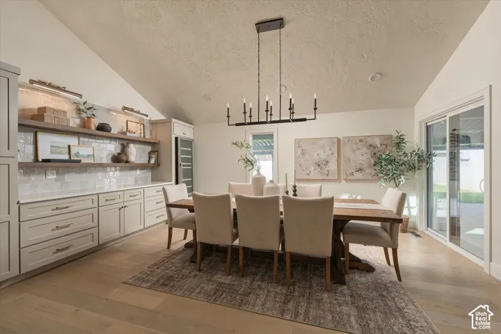 Vaulted ceilings, wood-finish flooring, custom built-in cabinetry, subway tile backsplash, and sliding glass door
