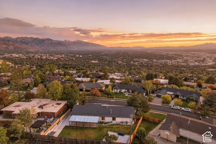 Aerial perspective featuring a manicured lawn, an attached patio cover, and expansive mountain range scenery