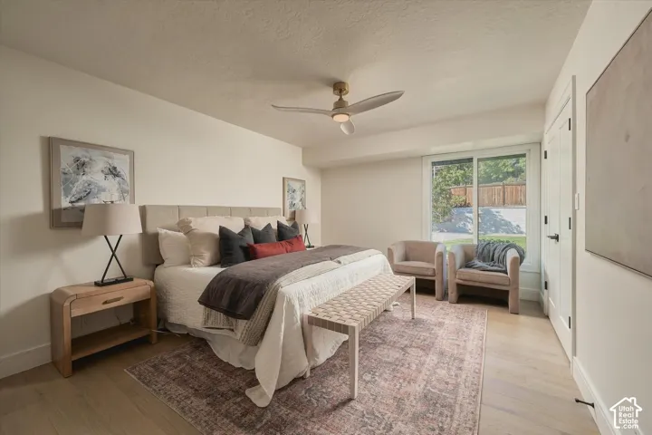 Neutral-toned room featuring wood-finish flooring, a contemporary three-blade ceiling fan with integrated lighting, and a sliding glass door