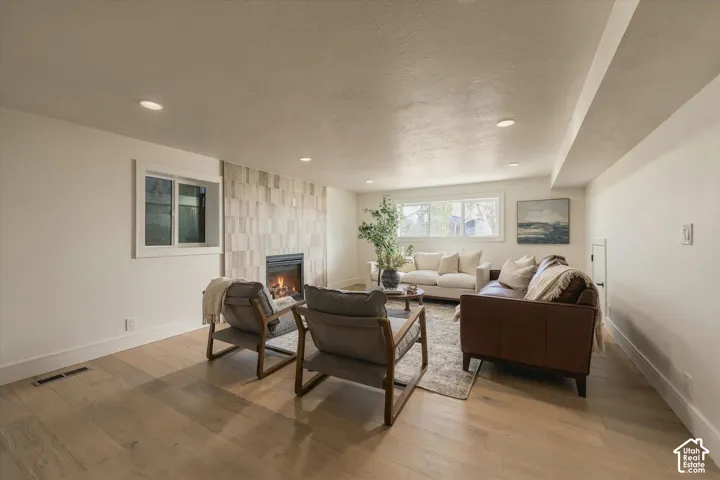 Living area featuring wood-finish flooring, recessed lighting, and a floor-to-ceiling textured tile fireplace surround