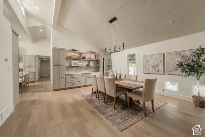 Vaulted ceilings featuring recessed lighting, wood-finish flooring, custom built-in cabinetry with integrated shelving, and a prominent multi-arm chandelier