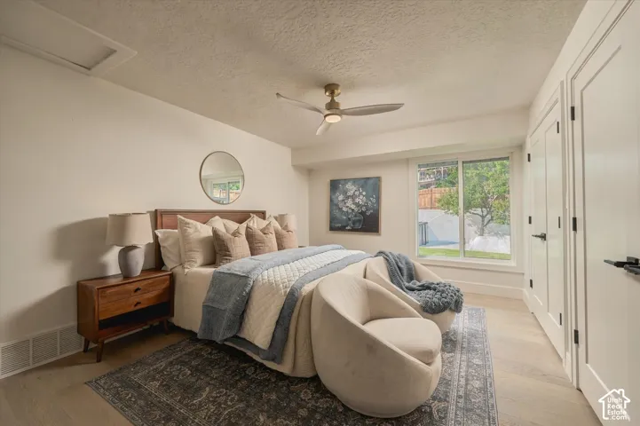 Room featuring wood-finish flooring, a sleek ceiling fan with integrated lighting, a sliding glass window, and a multi-panel door with matte black hardware