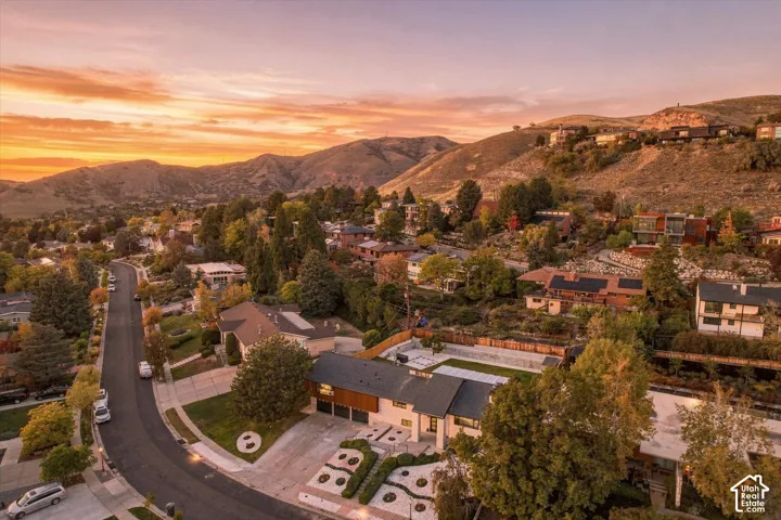Aerial perspective featuring a multi-level residence, a rectangular swimming pool, integrated solar panel arrays, a multi-car garage, and established mature landscaping