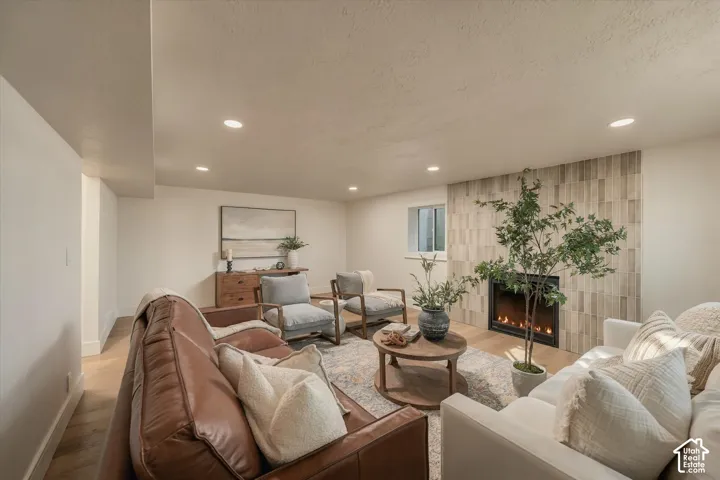 Fireplace featuring a full-height, vertically-oriented neutral stone tile surround, recessed lighting, and wood-finish flooring