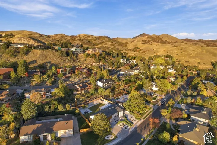 Aerial perspective featuring a residential lot with mature trees and mountain scenery
