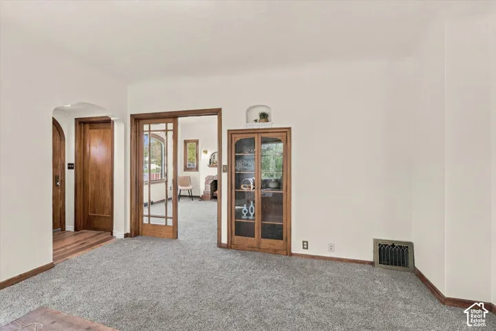 Interior space featuring wood-trim accents, built-in recessed cabinetry with glass doors, a decorative arched wall niche, and French-style paneled doors