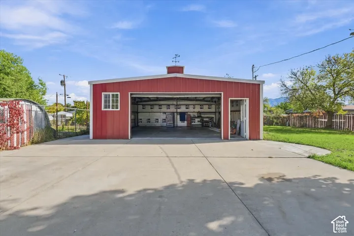 Detached workshop featuring a metal exterior, concrete apron, and a weathervane-topped cupola