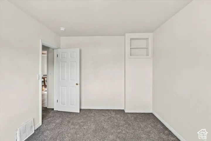 Interior room featuring wall-to-wall carpeting, a built-in recessed shelving unit, and a six-panel interior door