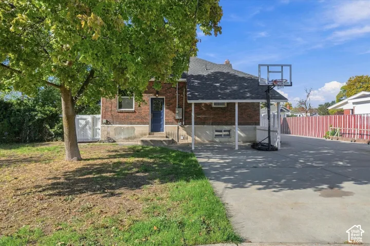 Brick exterior featuring a covered patio, concrete driveway, and mature landscaping