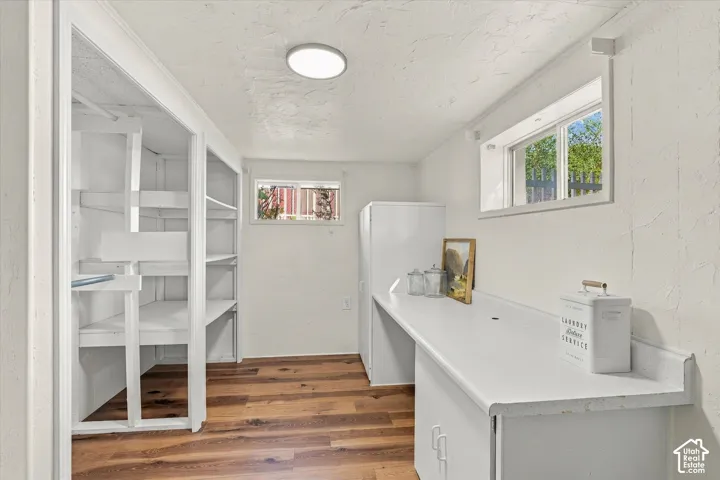 Utility room featuring wood-finish flooring, built-in shelving units, a long work surface, and two sliding windows
