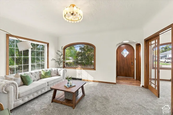 Living area featuring arched window detailing, wood-trim encasements, a custom wood door with diamond-shaped glass inlay, wood-framed French doors, and a decorative multi-tier flush-mount light fixture