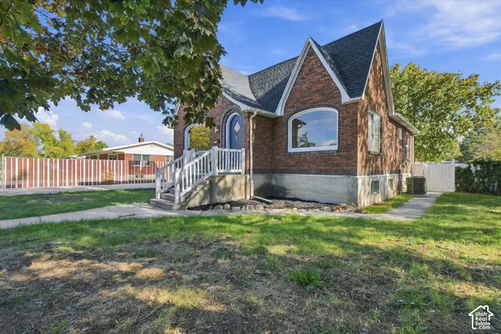 Brick exterior featuring a steeply pitched roofline, arched entryway, white  stairs, and a prominent arched window