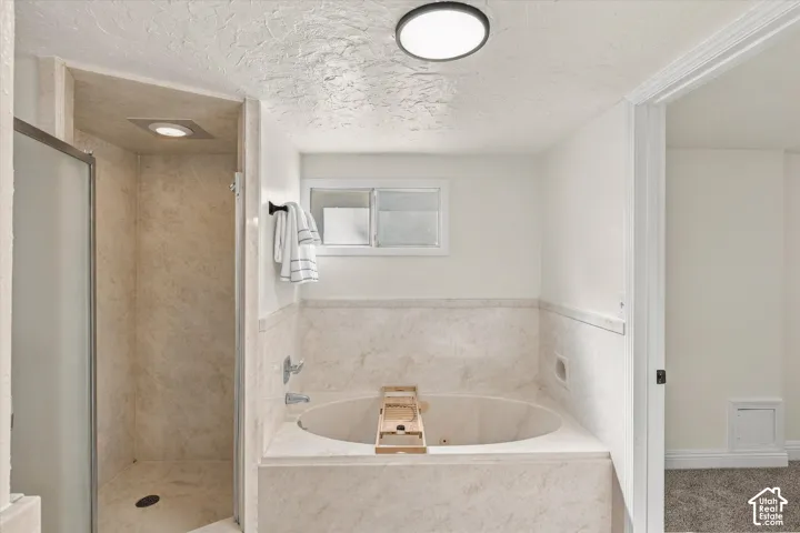 Bathroom featuring a deep soaking jetted tub, a separate shower enclosure with a glass door, and recessed ceiling lighting