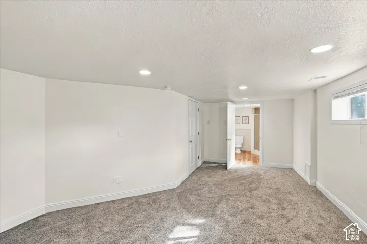 Interior room featuring neutral carpeting, recessed lighting, smooth-finish walls, and a high-set window
